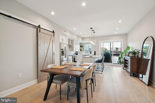 dining area featuring light wood-type flooring and a barn door