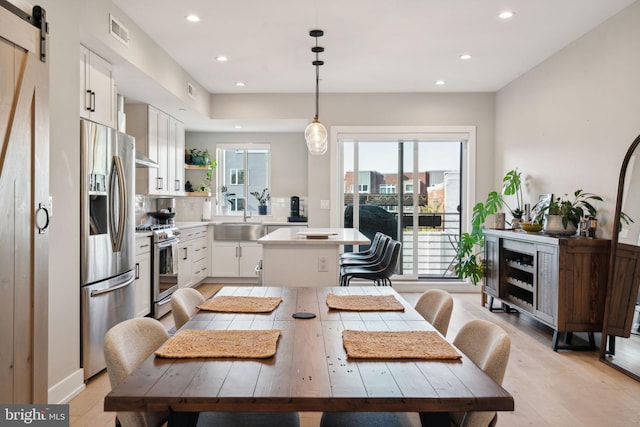 dining space with sink, a barn door, and light hardwood / wood-style flooring