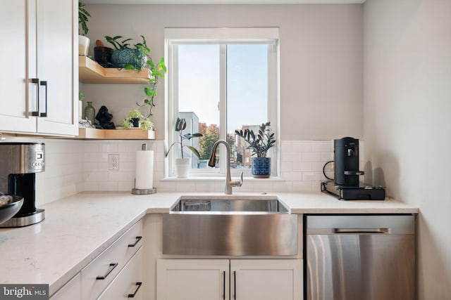 kitchen with decorative backsplash, sink, stainless steel dishwasher, white cabinets, and light stone counters