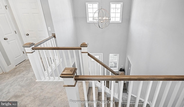 stairway with carpet flooring and an inviting chandelier