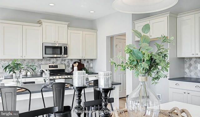 kitchen with white cabinets, decorative backsplash, stainless steel appliances, and wood-type flooring