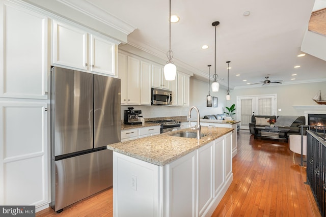 kitchen with a center island with sink, light wood-type flooring, white cabinetry, and appliances with stainless steel finishes