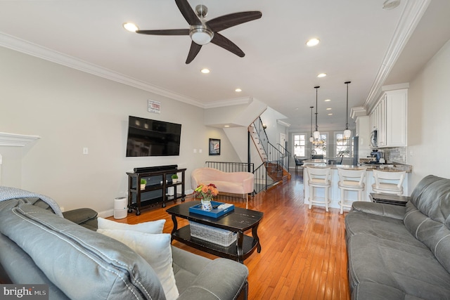 living room featuring light hardwood / wood-style flooring, ceiling fan, and ornamental molding