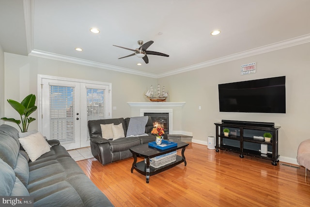 living room featuring french doors, light wood-type flooring, ceiling fan, and ornamental molding