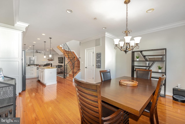 dining space featuring a chandelier, sink, crown molding, and light hardwood / wood-style flooring