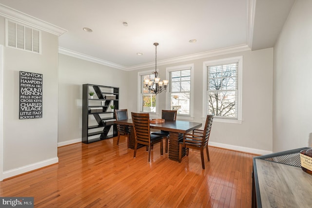 dining room featuring hardwood / wood-style flooring, ornamental molding, and an inviting chandelier