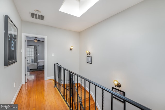 hall with wood-type flooring and a skylight