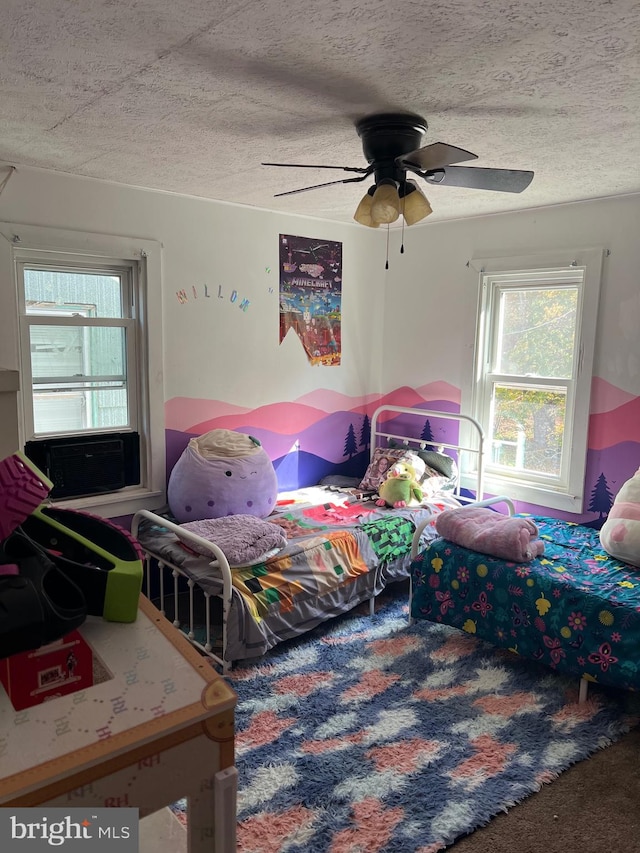 carpeted bedroom with ceiling fan and a textured ceiling