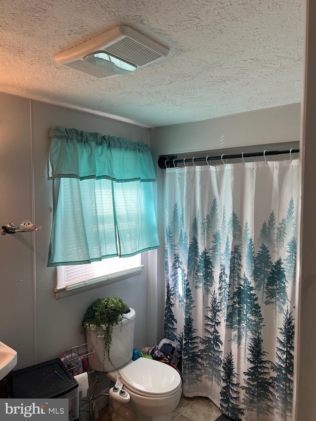 bathroom featuring toilet, a textured ceiling, tile patterned flooring, and a shower with shower curtain