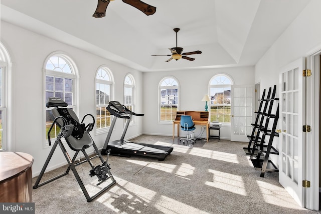 workout room with a tray ceiling, ceiling fan, and light carpet