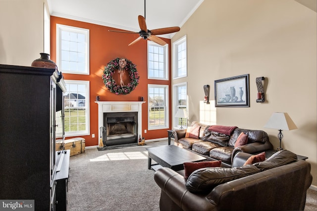 carpeted living room featuring ceiling fan, a towering ceiling, and crown molding