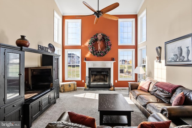 living room featuring ceiling fan, ornamental molding, light carpet, and a high ceiling