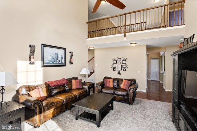 living room featuring ceiling fan, wood-type flooring, and a towering ceiling