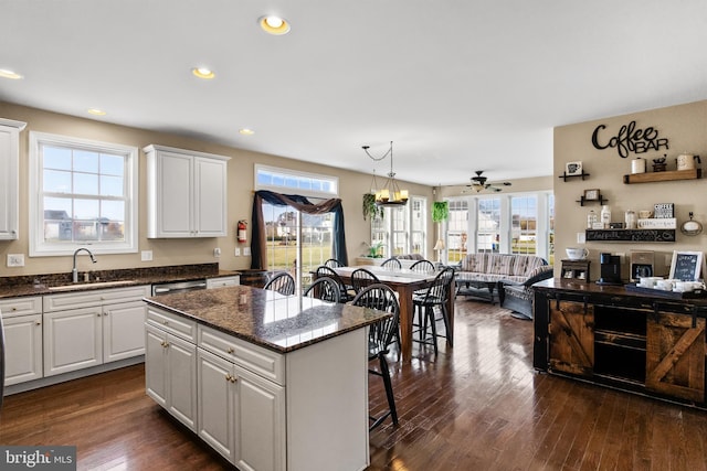 kitchen with pendant lighting, a center island, white cabinetry, and sink