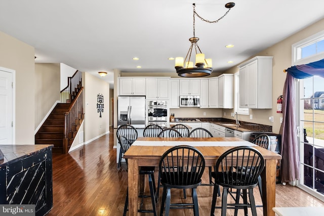 kitchen featuring dark hardwood / wood-style flooring, white cabinets, stainless steel appliances, and decorative light fixtures