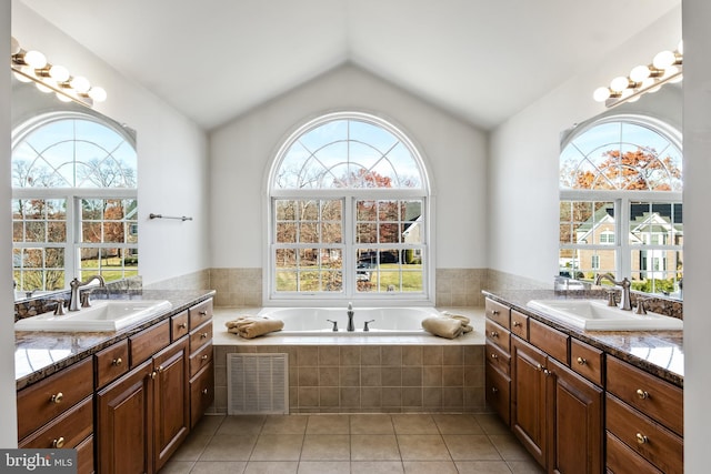 bathroom with tile patterned floors, a wealth of natural light, a relaxing tiled tub, and vaulted ceiling