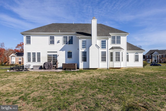 back of house featuring a yard, a hot tub, and a patio area