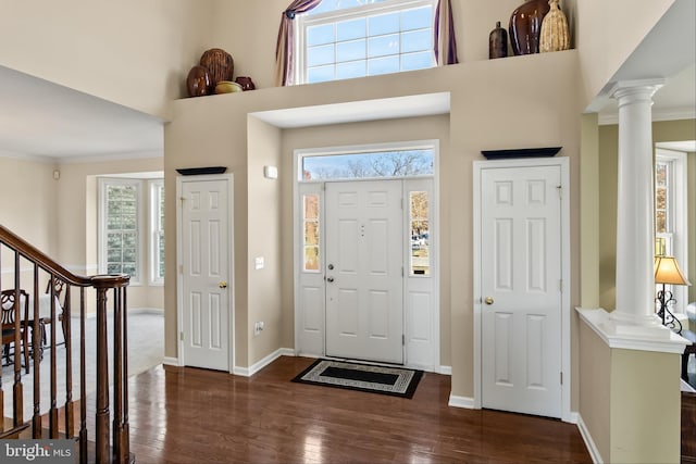 entryway with ornamental molding, dark wood-type flooring, a wealth of natural light, and ornate columns