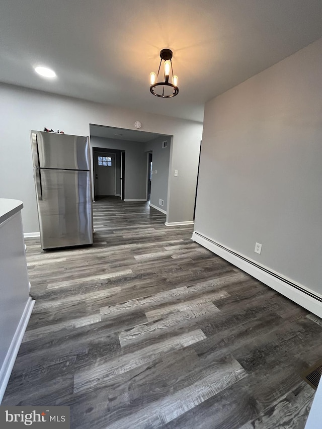 unfurnished dining area with dark hardwood / wood-style flooring, a chandelier, and a baseboard heating unit