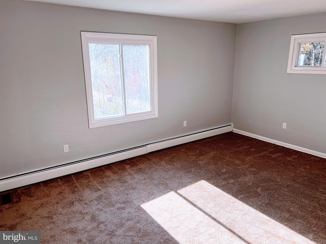 spare room featuring baseboard heating and dark colored carpet