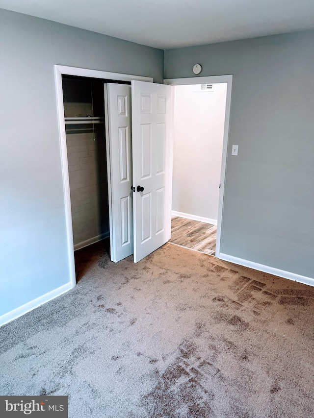 unfurnished bedroom featuring a closet and light carpet