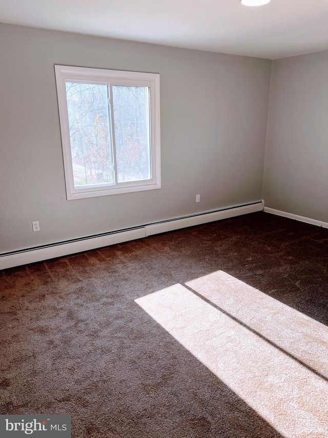 empty room featuring dark colored carpet and a baseboard radiator