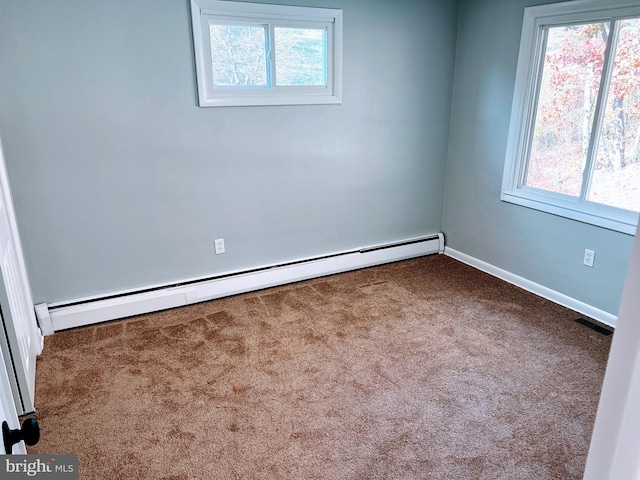 carpeted spare room featuring a healthy amount of sunlight and a baseboard heating unit