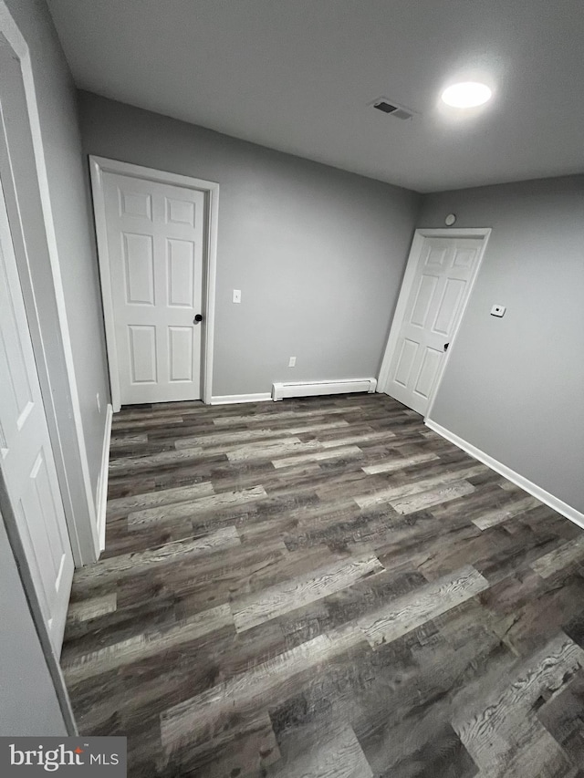 empty room featuring dark hardwood / wood-style flooring and a baseboard radiator