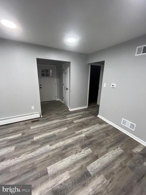 empty room with dark hardwood / wood-style floors and baseboard heating