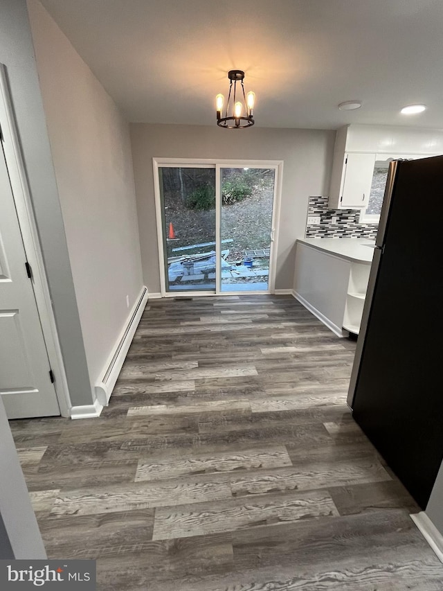 unfurnished dining area featuring a baseboard heating unit, a notable chandelier, and dark hardwood / wood-style floors