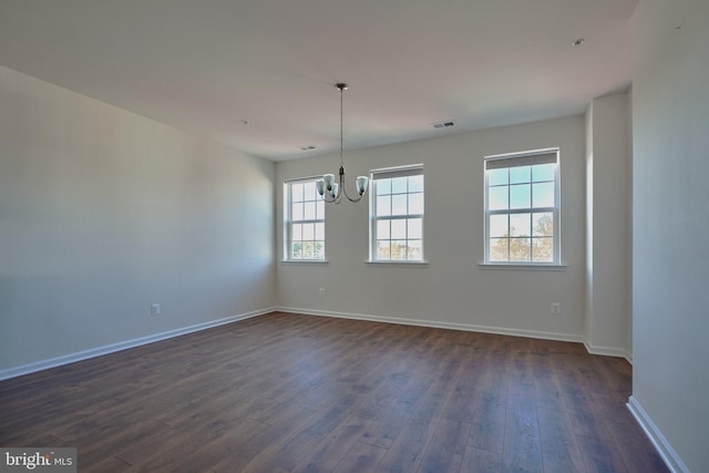 empty room with an inviting chandelier and dark hardwood / wood-style floors