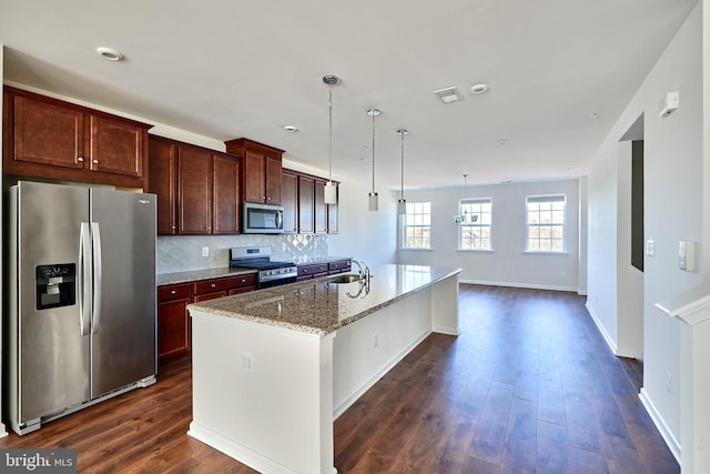 kitchen featuring a kitchen island with sink, stainless steel appliances, light stone countertops, and dark hardwood / wood-style flooring