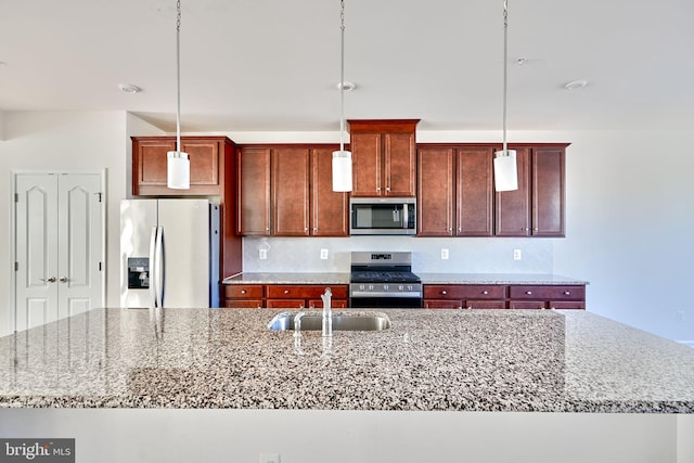 kitchen featuring appliances with stainless steel finishes, sink, pendant lighting, and a center island with sink