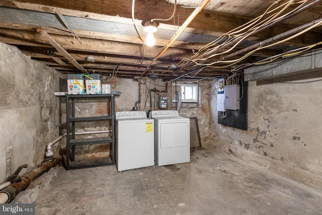 basement with electric panel and washing machine and clothes dryer