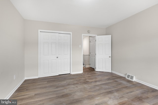 unfurnished bedroom featuring a closet and dark hardwood / wood-style flooring