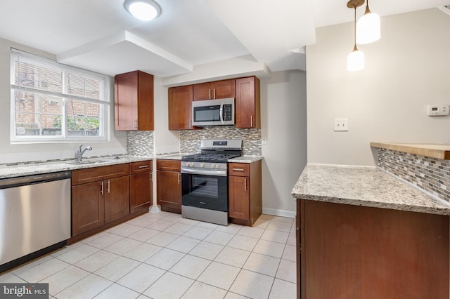 kitchen with sink, appliances with stainless steel finishes, light stone countertops, pendant lighting, and decorative backsplash