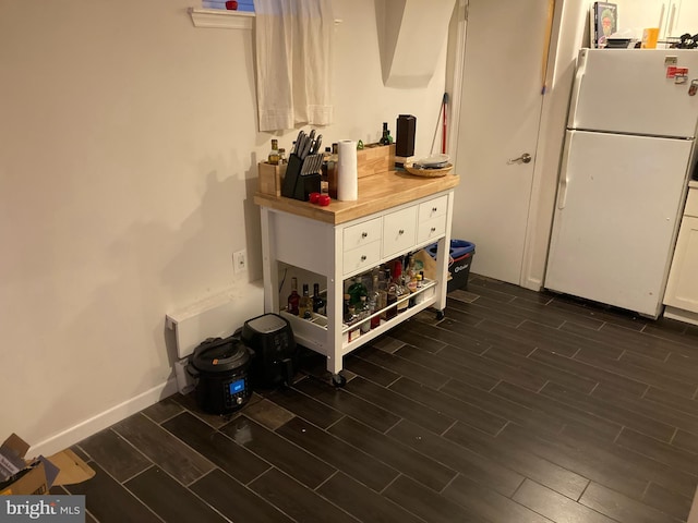 kitchen with dark wood-type flooring, white refrigerator, and white cabinets