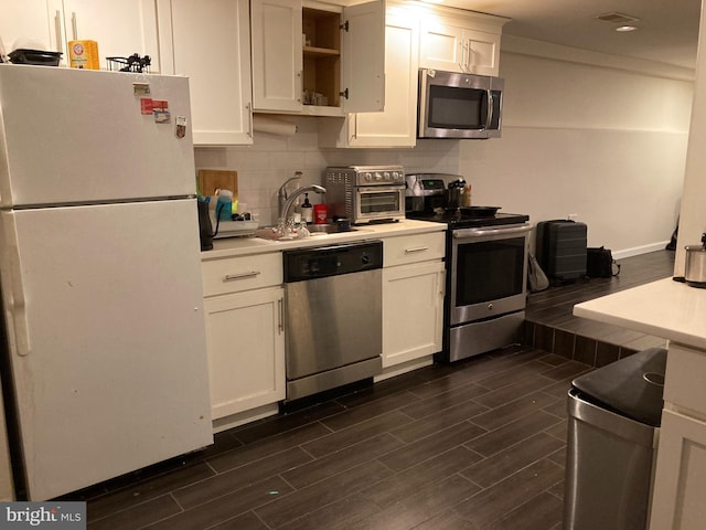 kitchen featuring white cabinetry, appliances with stainless steel finishes, and dark wood-type flooring