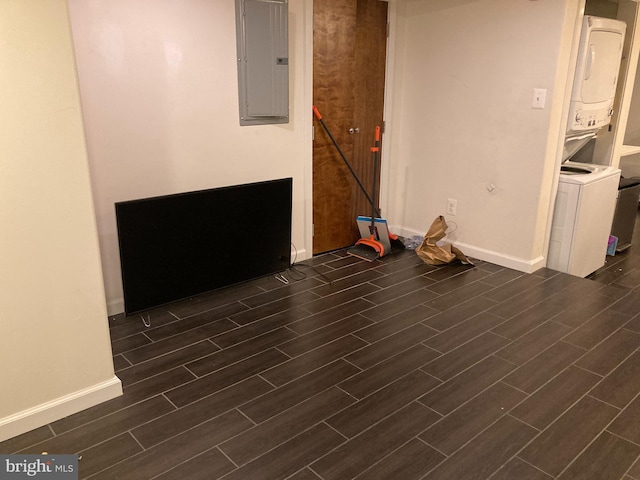 basement featuring stacked washing maching and dryer, electric panel, and dark hardwood / wood-style floors