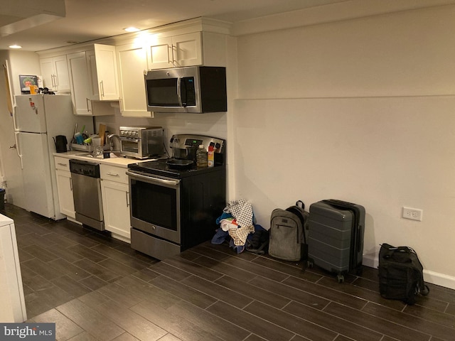 kitchen with dark wood-type flooring, stainless steel appliances, sink, and white cabinets