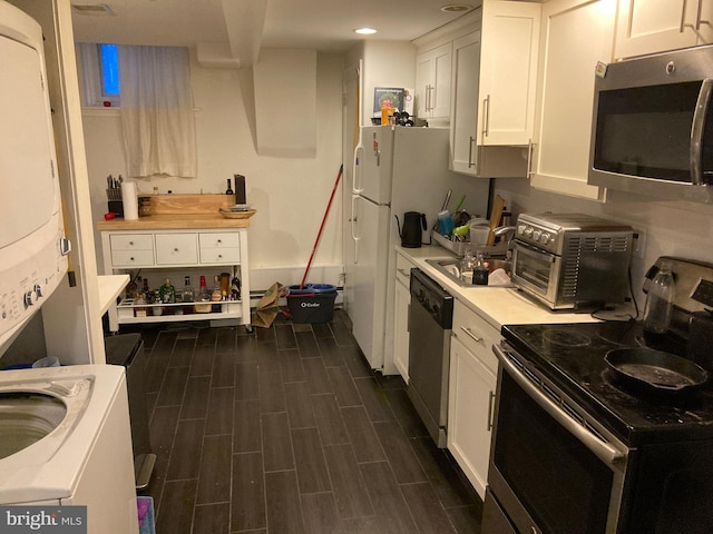 kitchen with stacked washer / drying machine, appliances with stainless steel finishes, dark hardwood / wood-style floors, and white cabinetry