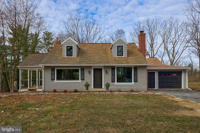 cape cod-style house featuring a front yard and a garage