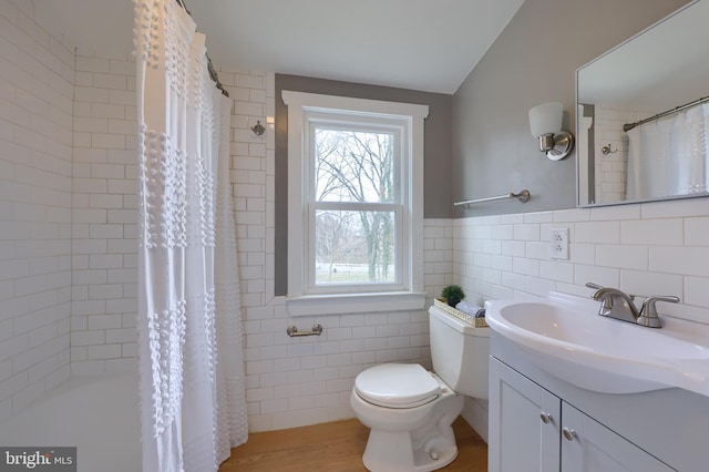 bathroom with wood-type flooring, vanity, toilet, and tile walls