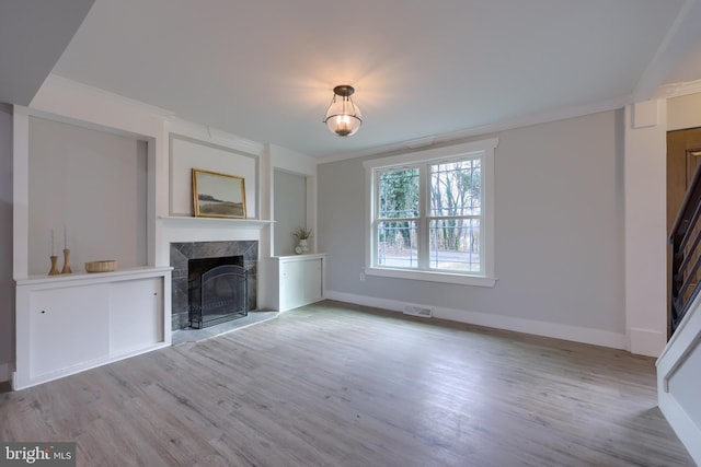 unfurnished living room featuring light wood-type flooring and a tiled fireplace