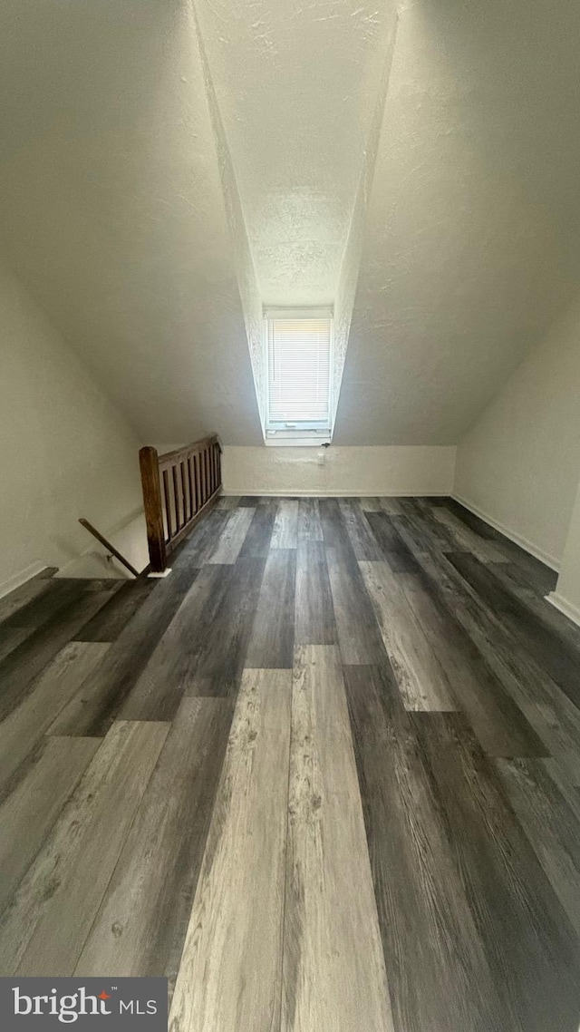 bonus room featuring lofted ceiling, dark hardwood / wood-style floors, and a textured ceiling