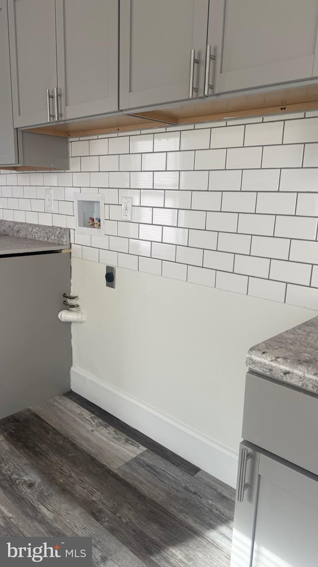 clothes washing area with dark hardwood / wood-style flooring, hookup for an electric dryer, washer hookup, and cabinets