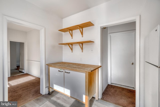 kitchen with light hardwood / wood-style flooring, wood counters, a baseboard radiator, and white refrigerator