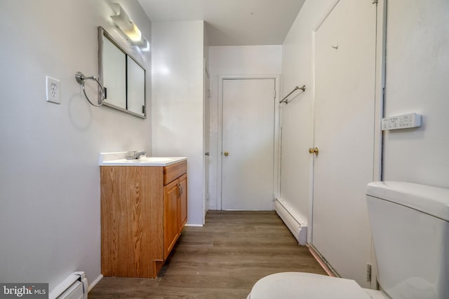 bathroom featuring vanity, toilet, a baseboard heating unit, and hardwood / wood-style floors