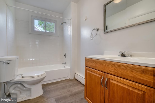 full bathroom with tiled shower / bath, hardwood / wood-style floors, a baseboard radiator, toilet, and vanity