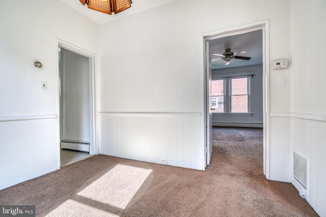 carpeted empty room featuring ceiling fan, a baseboard heating unit, and wooden walls